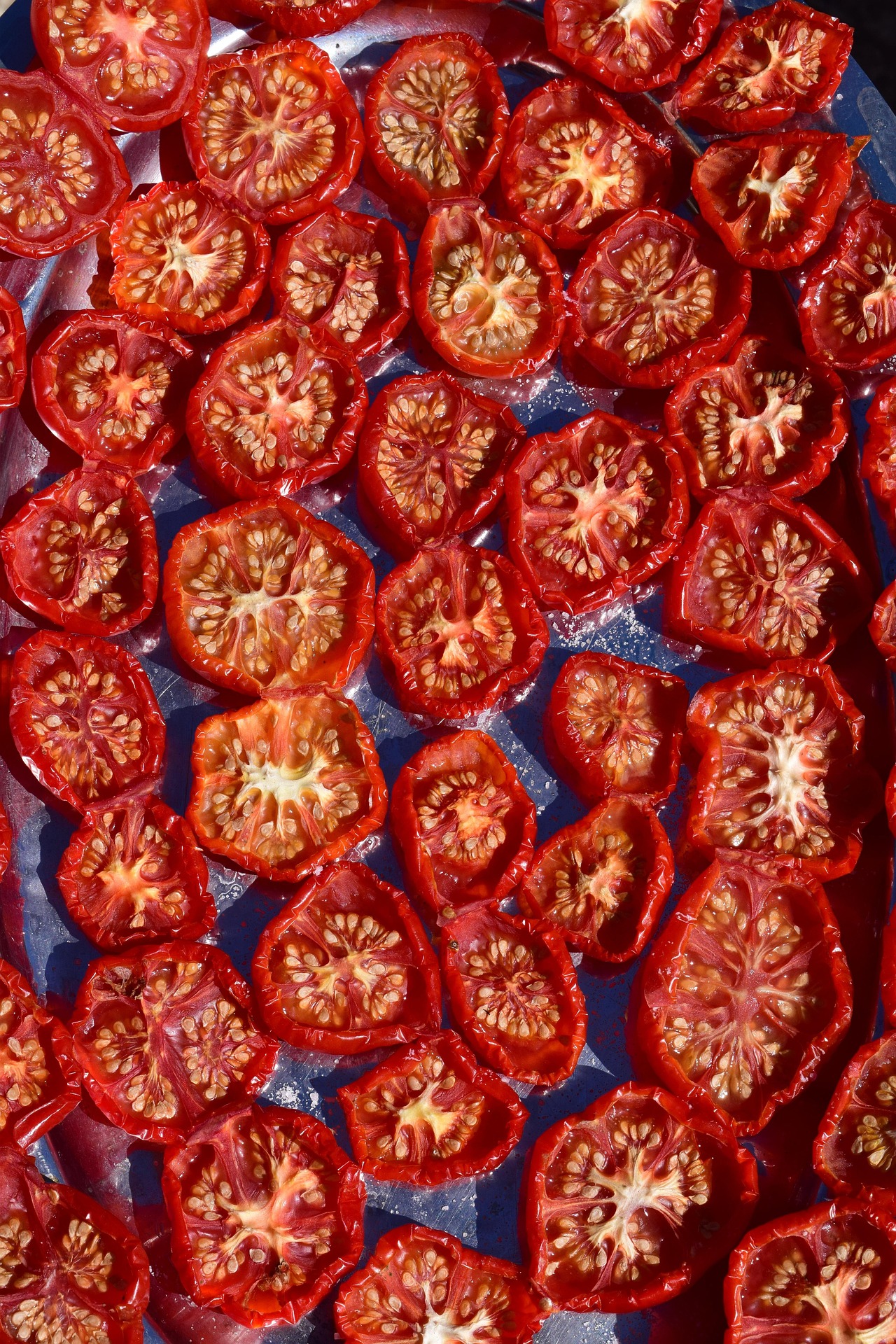 Wrinkled semi-dried cherry tomatoes on a baking tray after slow roasting for homemade sunblush tomatoes.